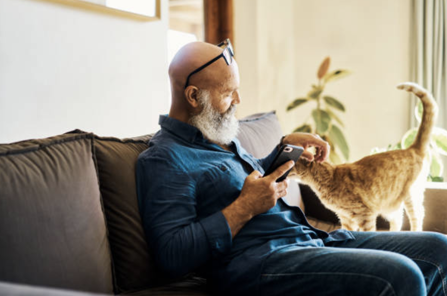 Man with phone in hand stroking ginger cat