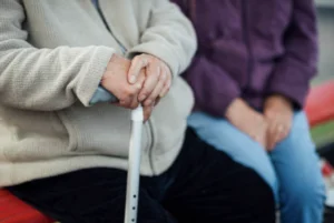 person sitting with walking stick at bus stop