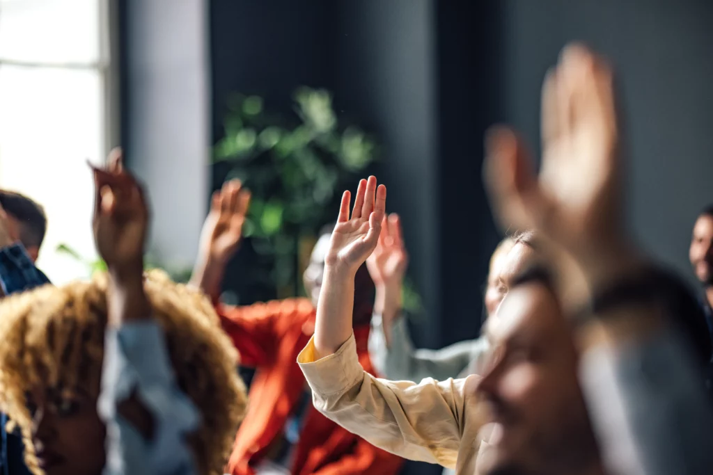 multiple hands in the air at a drug addict carers event